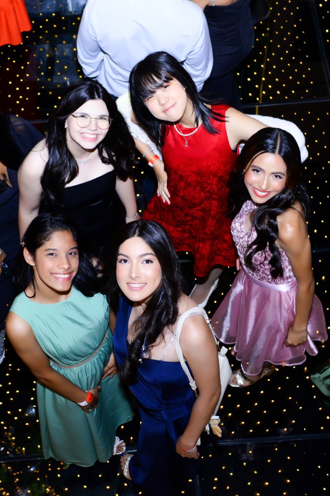 Formandas reunidas na pista de dança iluminada do baile de formatura